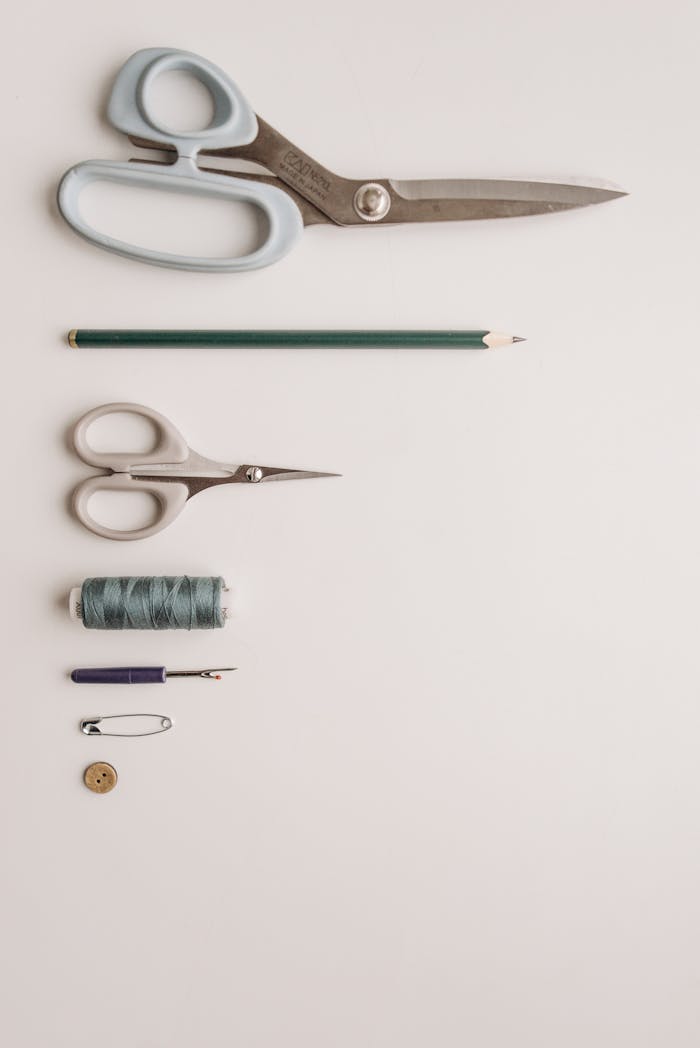 Organized flatlay of sewing tools and accessories on a neutral background, perfect for creative projects.